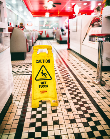 Slip and fall wet floor sign on a restaurant floor with checkered tile.