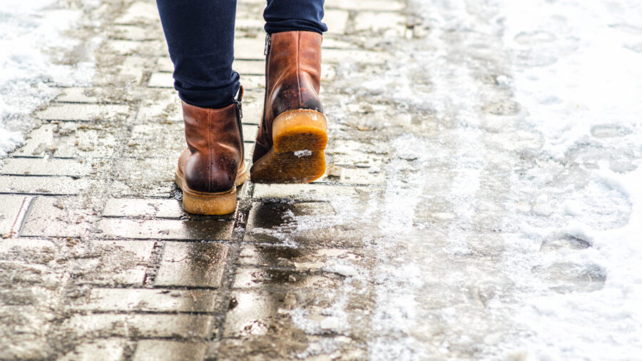 photo of a two feet walking down an icy sidewalk