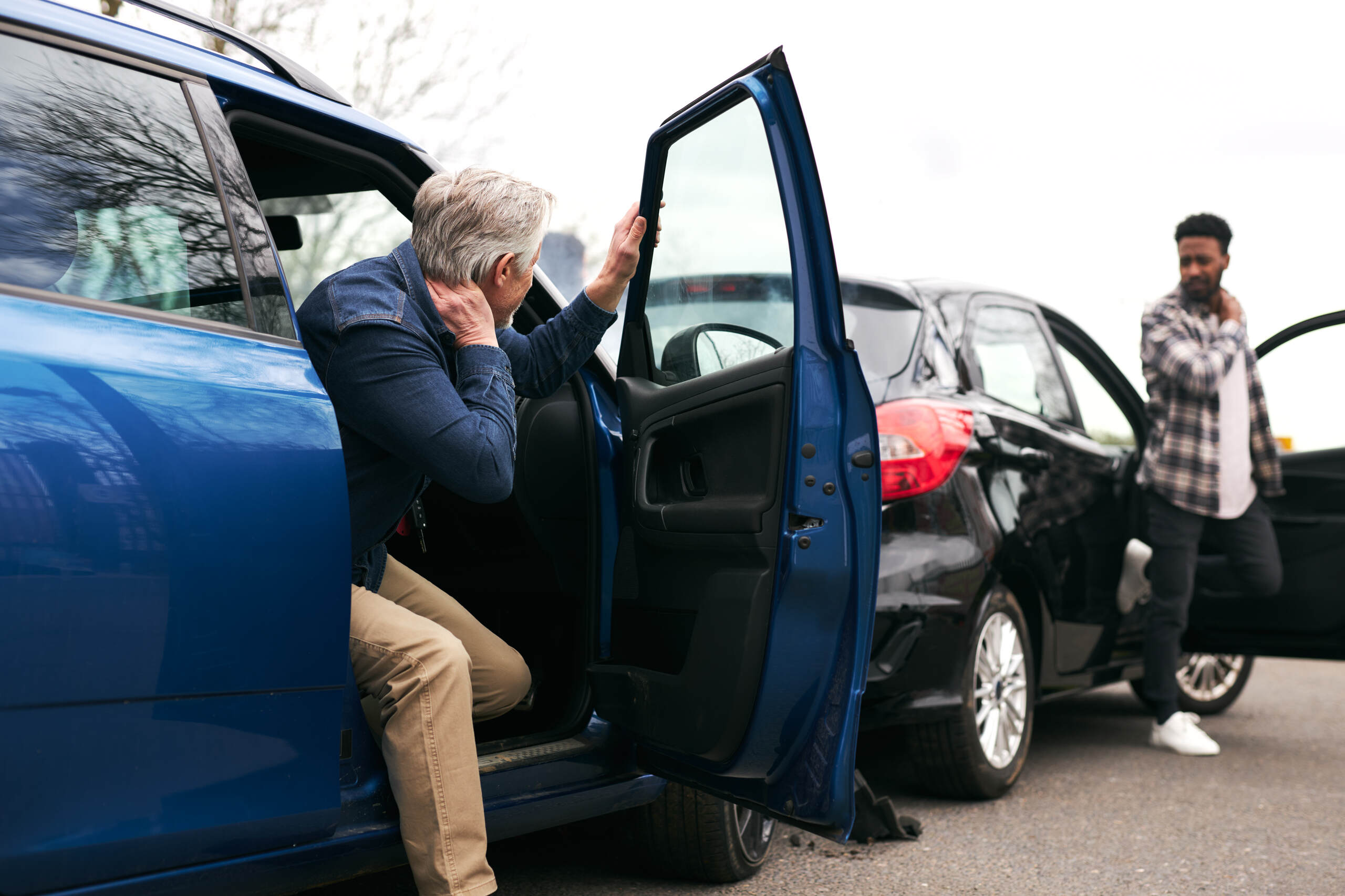Two drivers hold their necks in pain after a crash while considering what is whiplash worth in Nova Scotia injury claims.