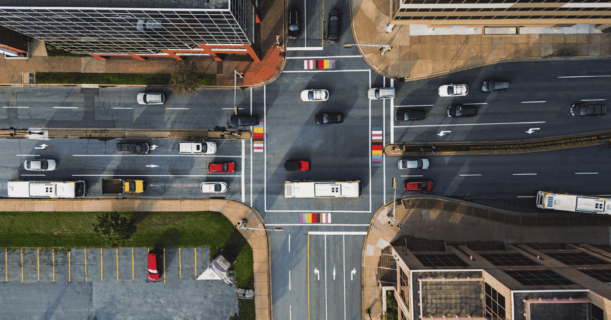 Aerial view of a city intersection with cars and buses navigating traffic lanes.